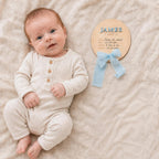 Newborn name sign resting beside a baby, birth stats written in by hand