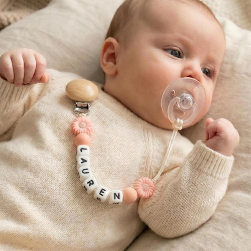 Newborn with a personalized daisy flower pacifier clip in peach and wood beads